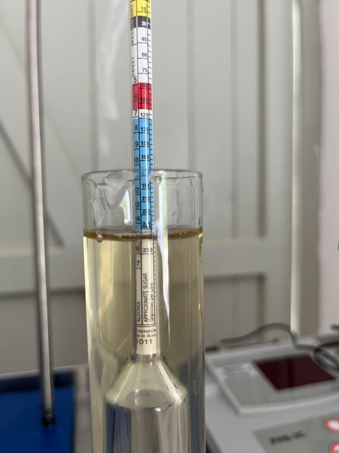 A hydrometer in a cylinder of grape juice